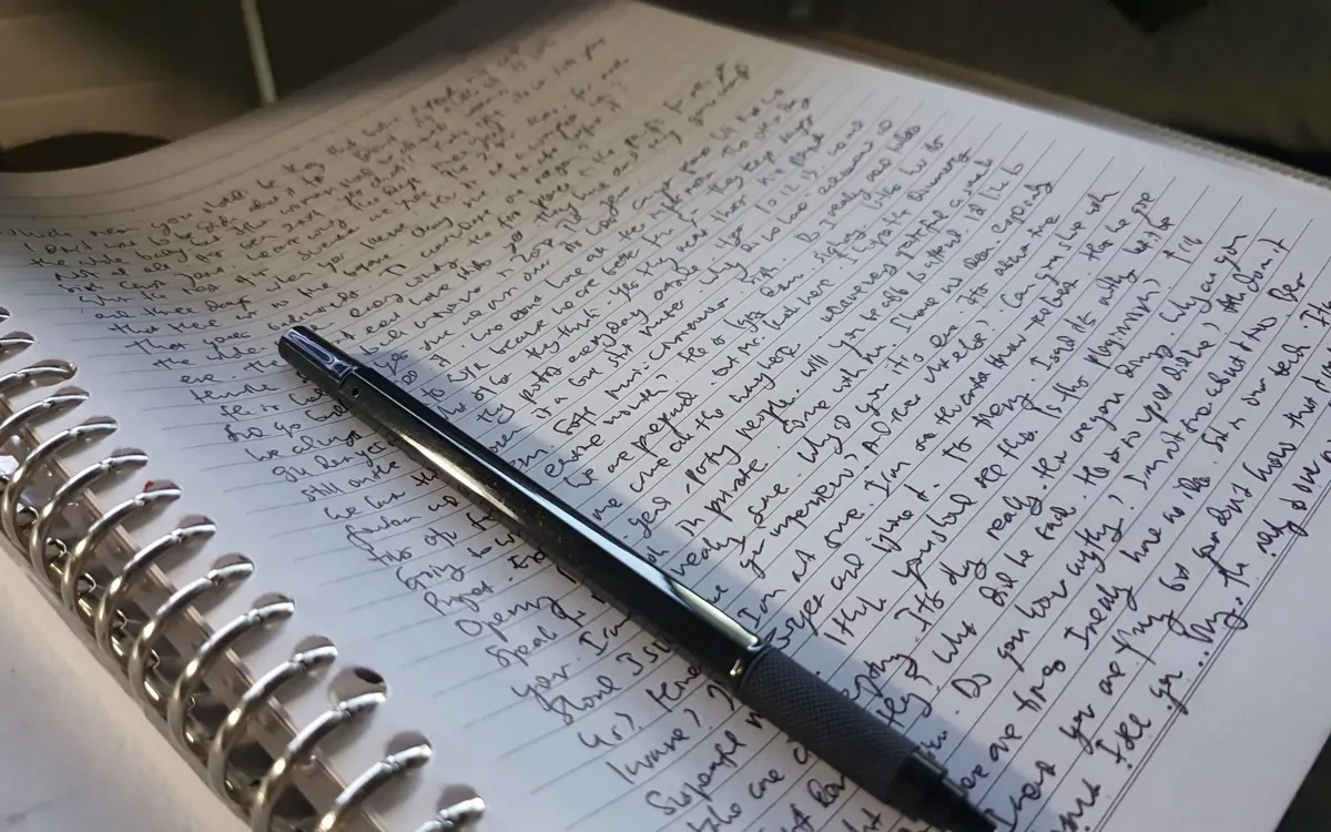 Handwritten notes in a notebook with a pen