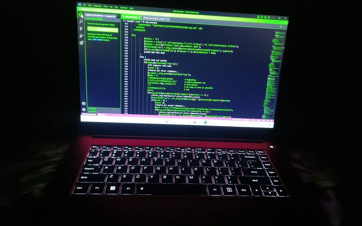 Laptop in a dark room showing green code on screen