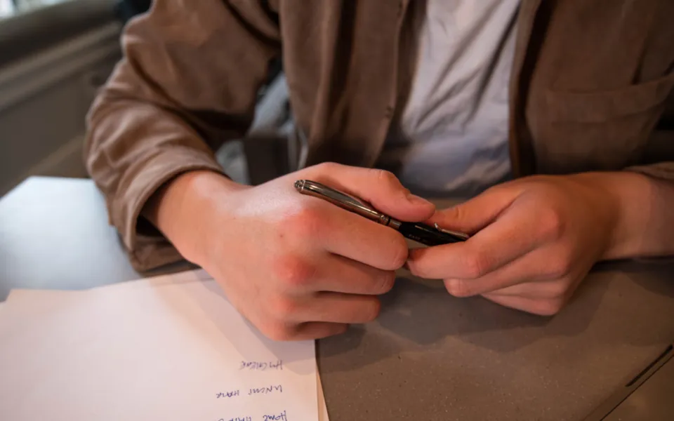 Hands holding a pen over handwritten notes