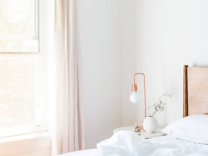 A freshly made bed in a bright, clean bedroom