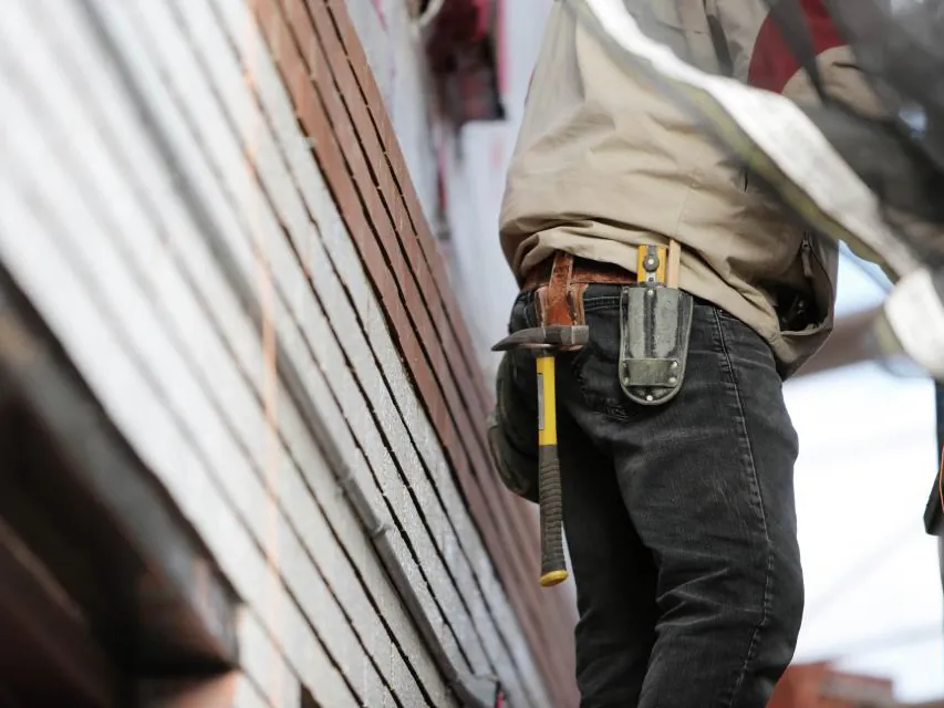 Builder with a tool belt working beside timber framing