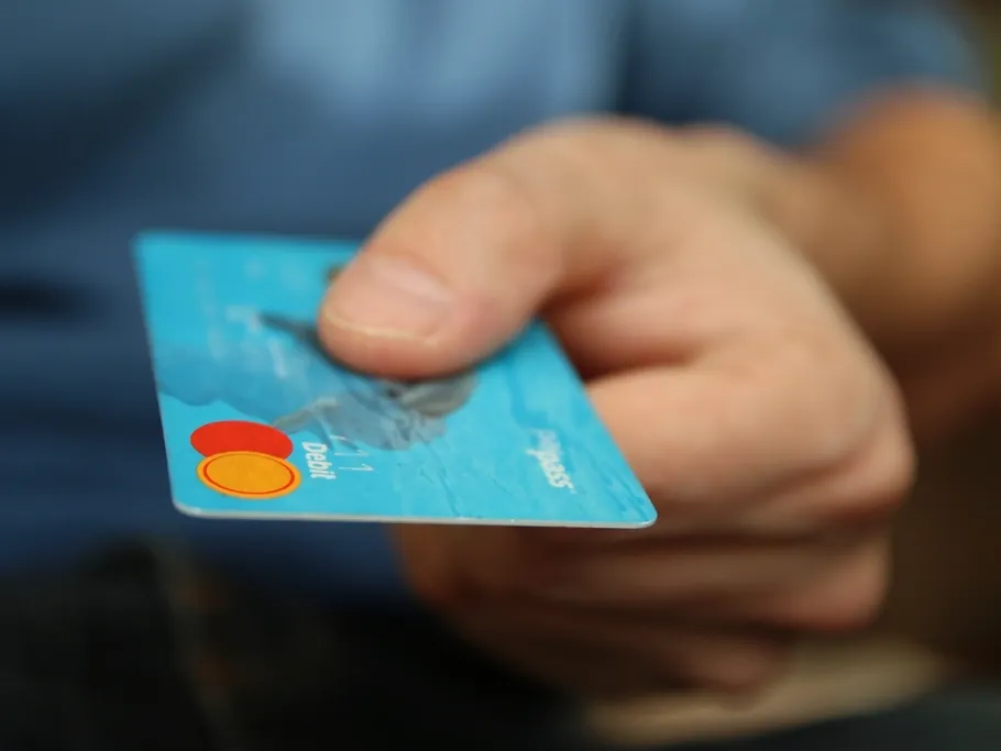 A hand holding out a payment card