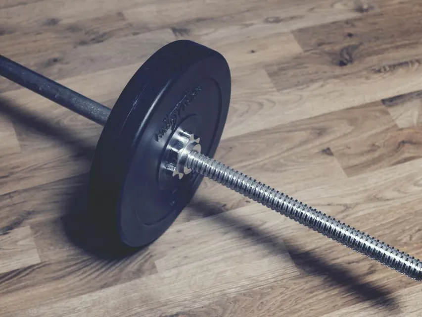 A barbell resting on a wooden gym floor