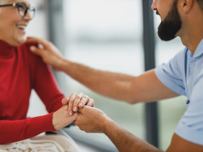 Carer holding an older woman's hands