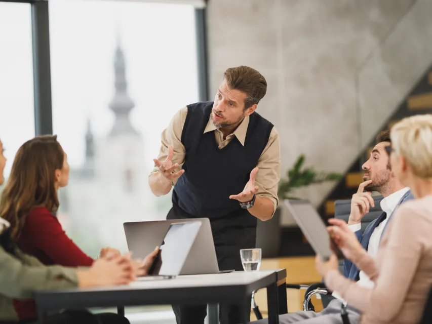 A man presenting to a small group around a meeting table