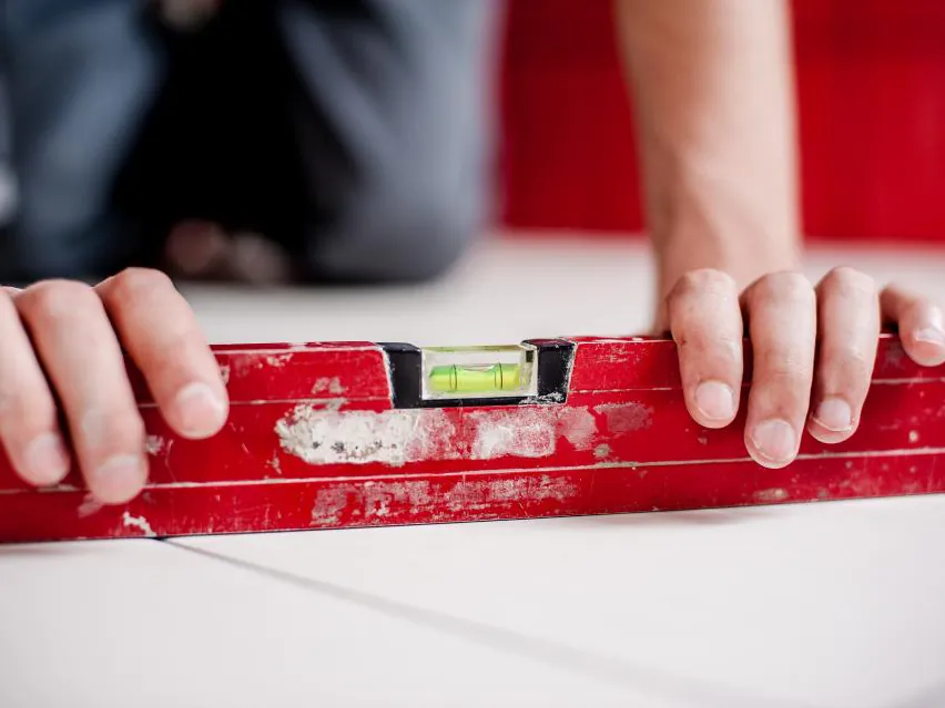 Hands holding a spirit level against a wall