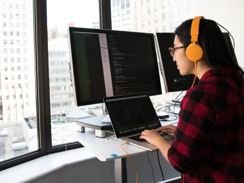 A developer working at two monitors by an office window